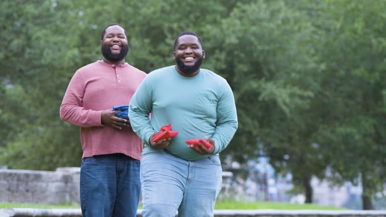 Two heavyset black men playing bean bag toss