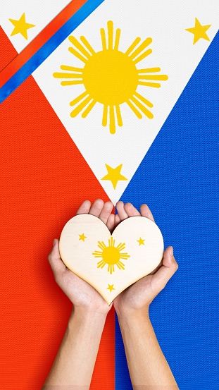 A human hand is holding a heart with the Philippine flag color. Philippines Independence Day concept