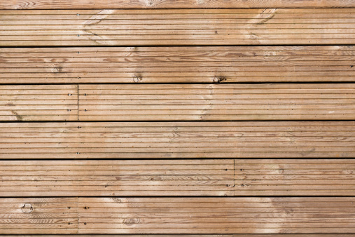 Full frame image of wooden decking flooring with grain pattern and screw heads.