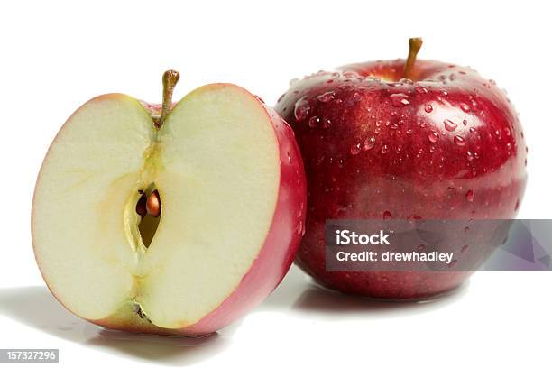 Two Rosy Red Apples With One Halved On White Surface Stock Photo - Download Image Now