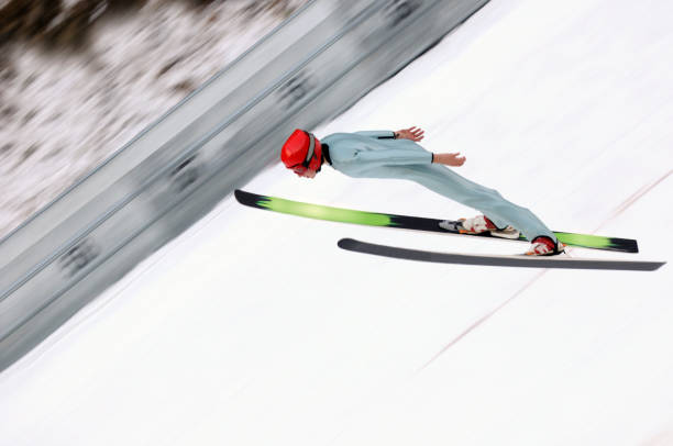 A ski jumper soars off a snowy ramp under a partly cloudy sky, displaying skill and grace.
