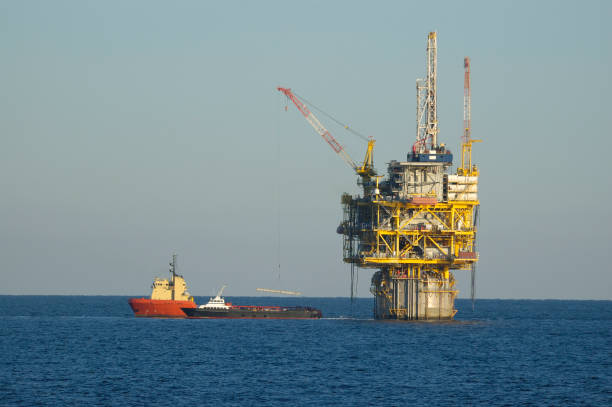 Wide angle aerial photo of a massive oil rig in a calm, blue ocean.