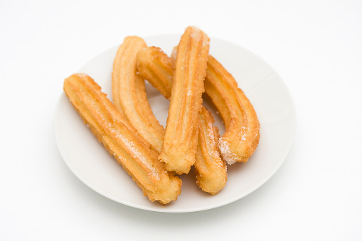 Homemade churros with cinnamon sugar on a plate served with chocolate sauce