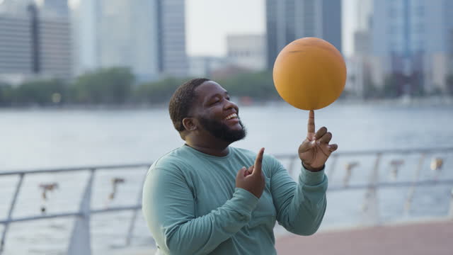 Young black man balancing basketball on finger