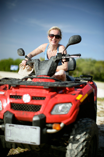 A woman on an ATV covered in mud.