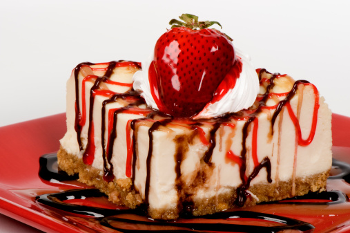 Cheese cake with a glazed strawberry and drizzled chocolate, carmel, and strawberry sauces.