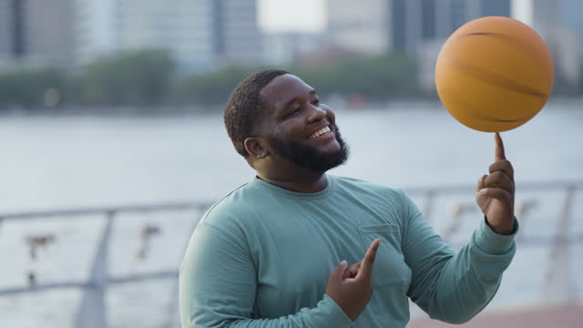 Young black man balancing basketball on finger
