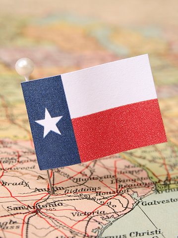Texan flag over more that sixty years old map pointing Austin city. Shallow depth of field