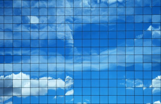 Sky and clouds reflected in a modern building glass facade.