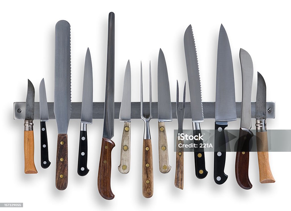 Kitchen knives on white A selection of kitchen knives and carving forks on a magnetic knife rack isolated on white. Combined outline clipping path excluding drop shadow. Kitchen Knife Stock Photo