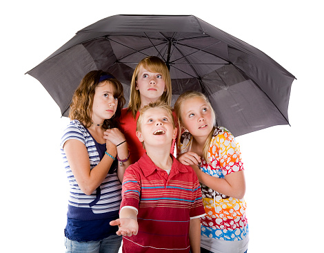 Four children huddled under an umbrella.