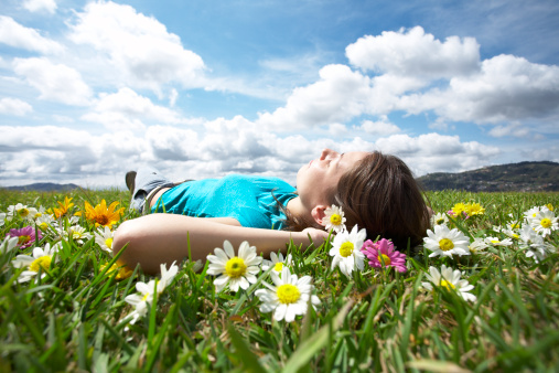 Portrait of smiling teen girl sitting on the field in grass and holding dandelion. The concept of carefree, freedom and psychology.