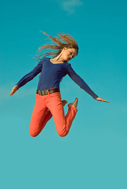 istock jumping girl on blue sky background 157329500