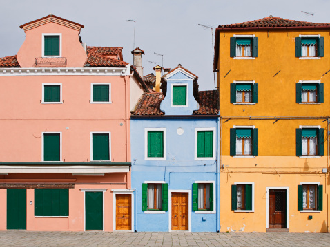 Sunrise in colorful fishing village Burano, Italy; boats and buildings reflect in calm water