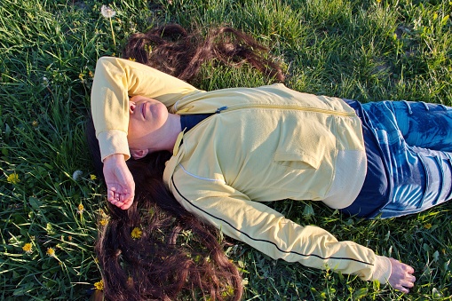 Young woman outdoors lying down in field during sunset