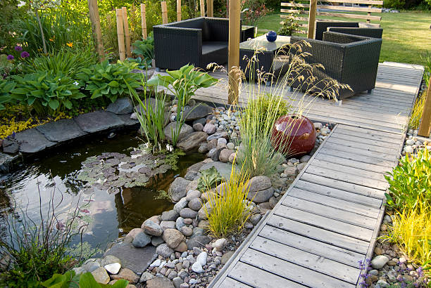 Patio and pond in the afternoon sun A beautiful small pond and a patio with a sitting area.  garden feature stock pictures, royalty-free photos & images