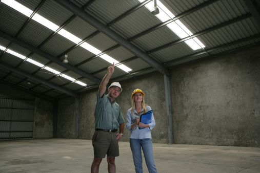 Man and woman surveying empty shed.