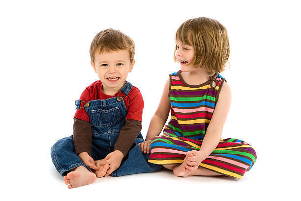 Small boy and girl sitting together smiling on white stock photo