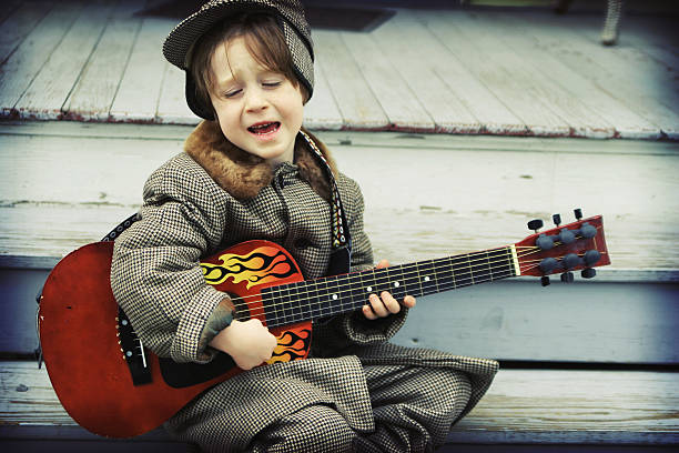 Cute Child Playing Guitar and Singing- Rockabilly Boy Adorable little boy in vintage suit, sings with great expression and plays small red guitar with flames. rockabilly boys stock pictures, royalty-free photos & images