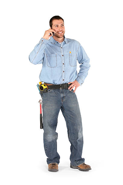 Male isolated on white with toolbelt on talking on the phone ready to work.