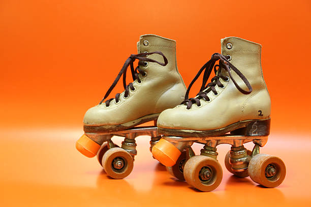 Pair of orange and brown four-wheel rollerblades with laces stock photo