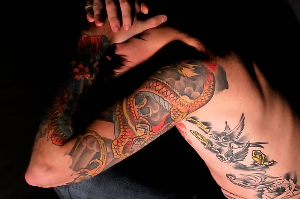 istock Tattooed youth holding head in his hands 157330688