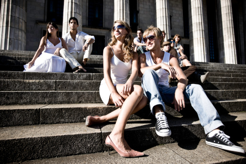 group of students sitting in front of the Buenos Aires university building, enjoying the afternoon sun.