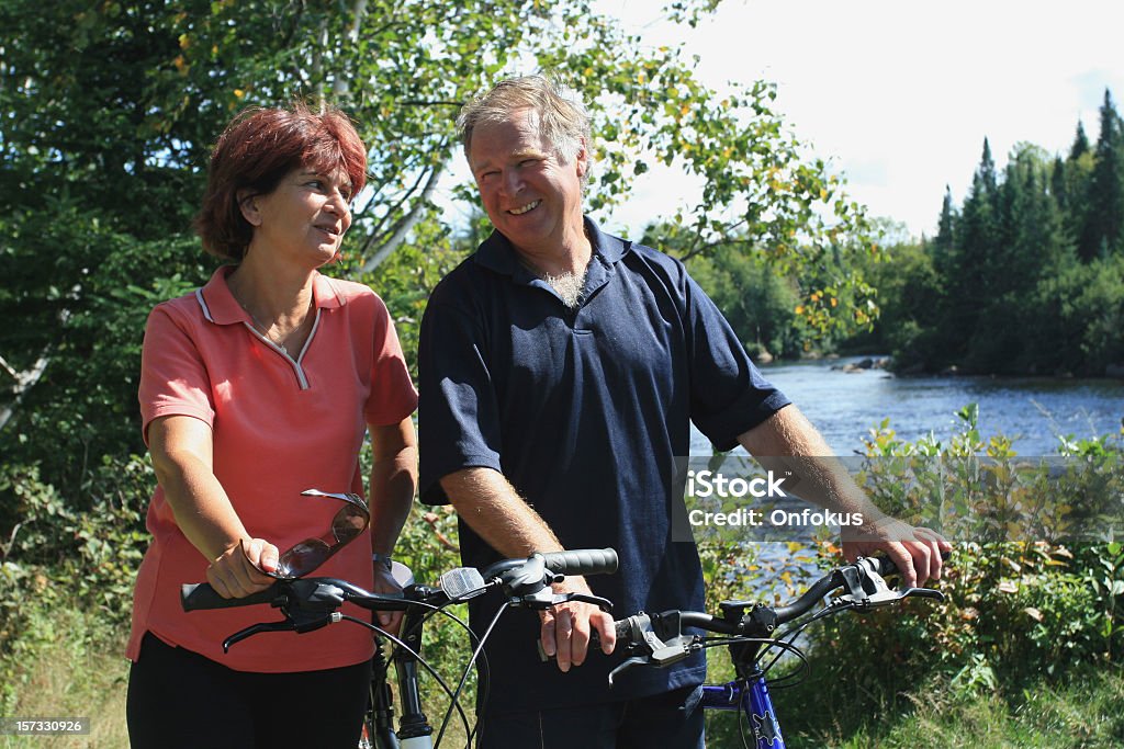 Feliz casal sênior na floresta de bicicleta no verão - Foto de stock de 55-59 anos royalty-free