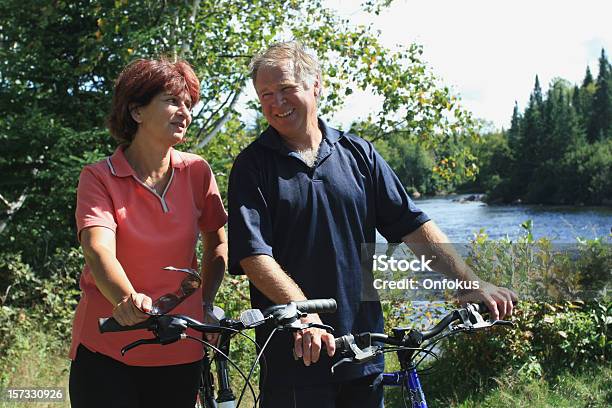 Foto de Feliz Casal Sênior Na Floresta De Bicicleta No Verão e mais fotos de stock de 55-59 anos