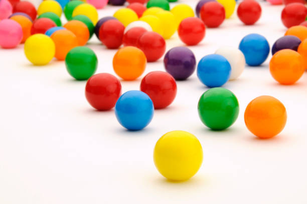 Festive, Colorful Gum Balls Candy Rolling, White Background Surface Colorful Gum Balls; close-up and eye-popping. There is space for copy and graphics. gobstoppers closeup stock pictures, royalty-free photos & images