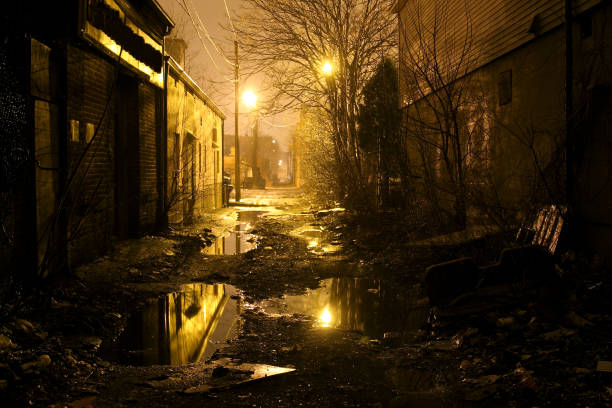 Dark urban inner city alley reflecting in puddles. Photo taken of a dark shadowy atmospheric back alleyway  