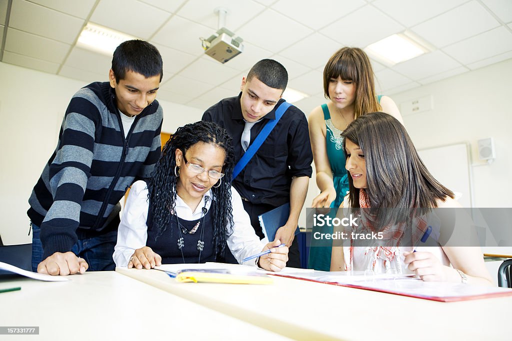 further education: diverse class tutorial with teacher helping her pupils  16-17 Years Stock Photo