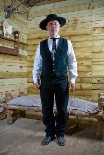 Preacher standing stiff in his simple wooden bedroom. Traditional Wild West Portrait.