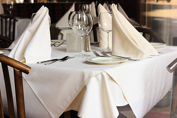 Restaurant Table Setting Linens Glasses Silverware A restaurant dinner table under natural light has been set with linens, silverware and stemware, and awaits its dinner clientele. napkin photos stock pictures, royalty-free photos & images