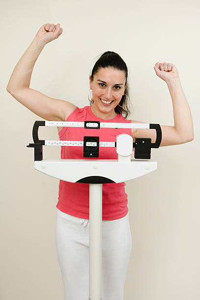 istock happy woman on weight scale 157332078