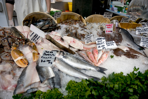A selection of seafood in polystyrene cool boxes, being kept cold in ice at a market stall in Northumberland. There are signs in the boxes to notify the customer of what is on sale.