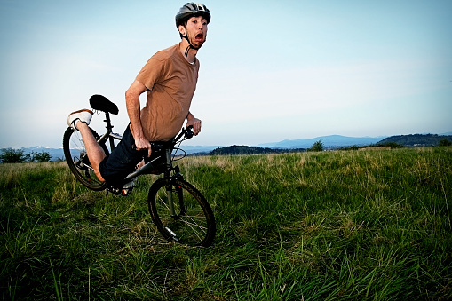 Man in sports helmet carrying mountain bike