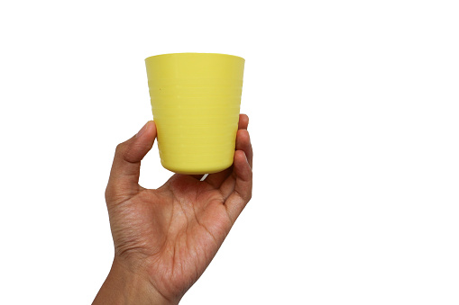 Hand holding a yellow plastic cup isolated on the white background