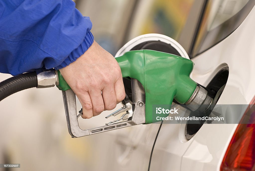 Refueling Automobile With Gasoline Pump Nozzle Shallow depth of field.  Focus on hand and pump handle. Car Stock Photo