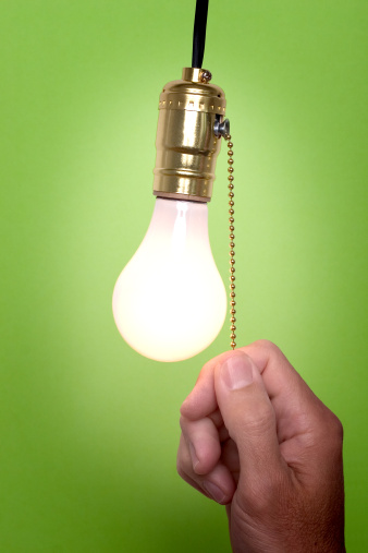 Hanging light bulb with pull switch.  Person is turning on or off the light.