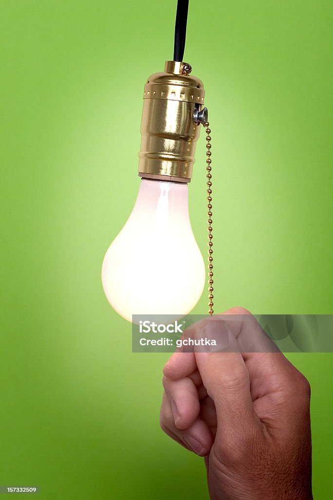 Don't forget to turn the light off! Hanging light bulb with pull switch.  Person is turning on or off the light. Turning On Or Off Stock Photo