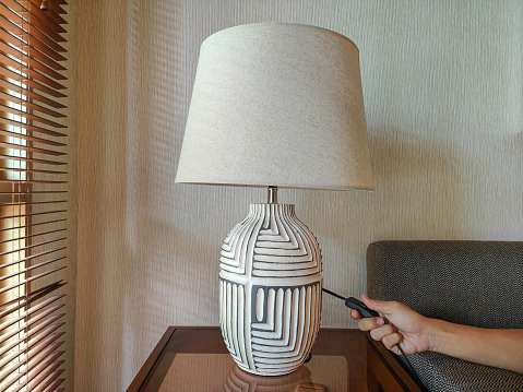 Close-up shot of unrecognizable hand turning off table lamp
