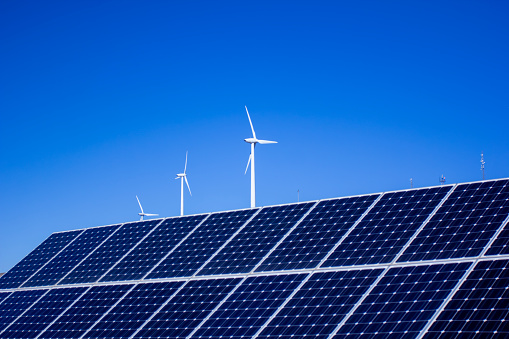 Solar panel and wind turbine against blue sky. High quality photo