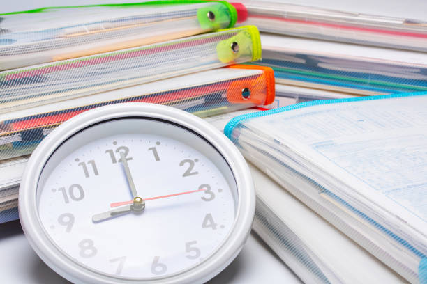 Clock and a large amount of document files. Image material of Working hours, Deadlines, Overtime.