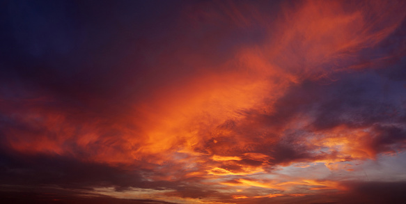 Soft clouds with the hint of the sun at sunset. Many orange tones and patterns of clouds. 