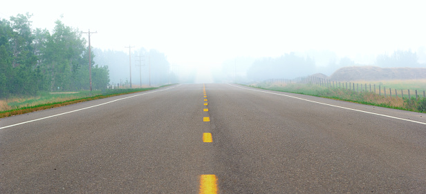 Empty highway in countryside covered with thick smoke during wildfires in summer, no visibility.