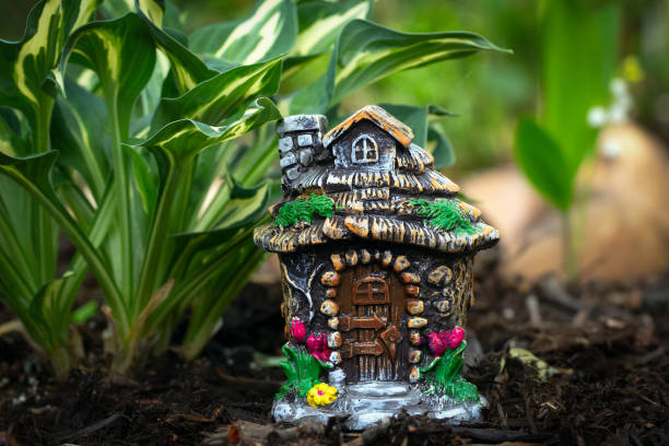 istock Decorative tiny gnome house is among flowers in the garden. 1573328298