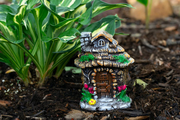 istock Decorative tiny gnome house is among flowers in the garden. 1573328309