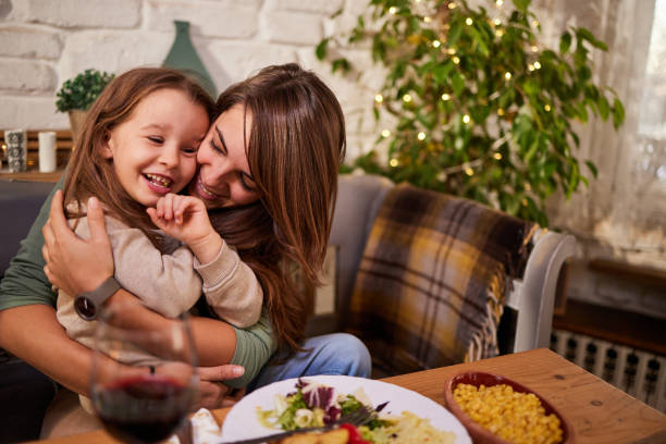 istock Loving single mother and daughter embracing at dining table. 1573328361