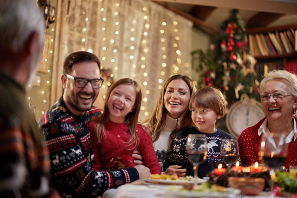 istock Cheerful extended family talking during Christmas dinner at home. 1573328369